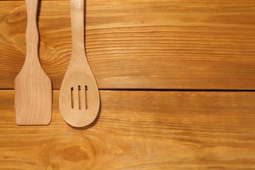 The composition of wooden spoon and kitchen spatula lying  on a panel of vintage brown boards with free space for text advertising of food or restaurant menu design.