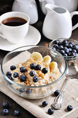 Oatmeal or porridge with blueberries, bananas, and brown sugar. Healthy breakfast. Toned image, selective focus