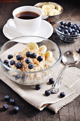 Oatmeal or porridge with blueberries, banana, and brown sugar. Healthy breakfast. Toned image, selective focus