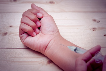 Hand holding syringe with filter effect retro vintage style