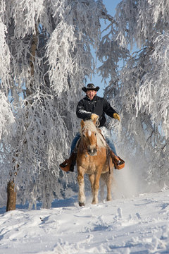Man on horse riding through snowy landscape
