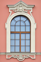 Fototapeta na wymiar Window with arch and a bas-relief on a background of pink wall. From the series window of Saint-Petersburg.