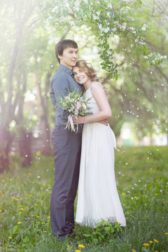 Love couple standing among blooming apple tree