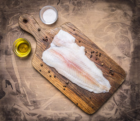 crude Pangasius on a cutting board with butter and salt on wooden rustic background top view close...
