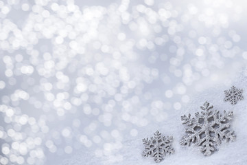 Glass toy snowflake on snow background.