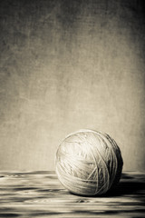 Clew of yarn on new wooden board and burlap background. Toned