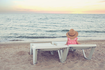 toddler with big hat sitting on the beach