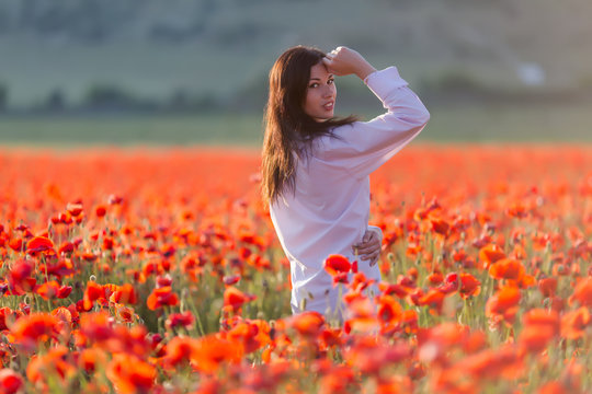 Girl at blooming poppy field