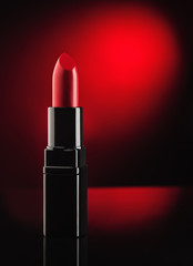 Red lipstick on black, reflective, mirror background. Background for cosmetic or beauty advertising.