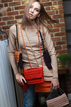 Model posing with knitted handbags