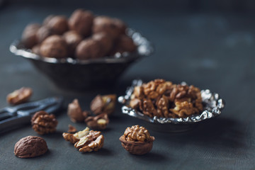 Walnuts in a bowl, whole and chopped on grey wooden table. Vintage style