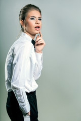 Beautiful young woman wearing a shirt and bow tie against a gray background