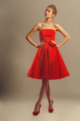 Confident model in a red flowing dress in studio