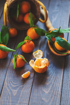 Fresh mandarin oranges fruit with leaves in old wooden spoon on table. Group of mandarin fruits and leaves in a basket