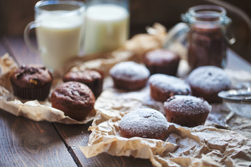 Glass of milk and chocolate cupcakes on a wooden background