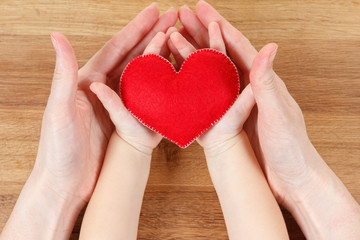 Hands of mother and son holding heart symbol
