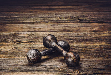 Old iron dumbbells on an old wooden table. Image taken from above, low angle.