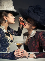 Girls drink cocktails and feed each other cherries