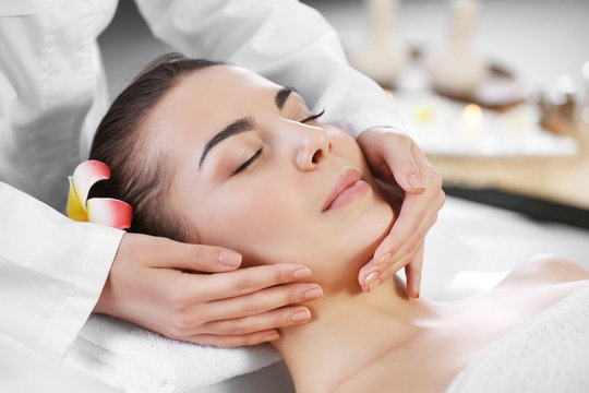 Beautiful young woman relaxing with face massage at beauty spa