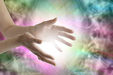 Beaming healing energy - Outstretched female healing hands with white light between and a vibrant multicolored flowing   energy field background