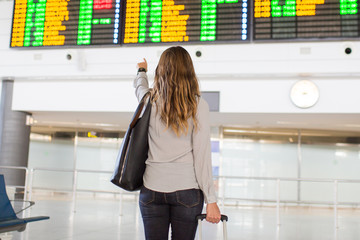 Frau vor Anzeigetafel am Flughafen 