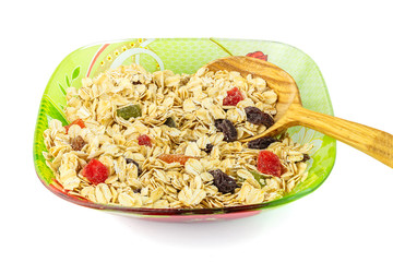 Oat flakes with dried fruit on plate with wooden spoon, isolated on white background