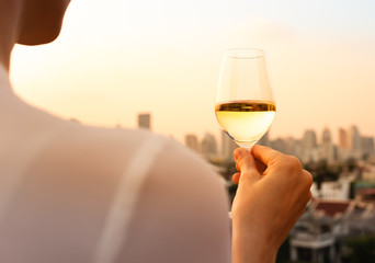 Woman enjoying a glass of wine and city views.
