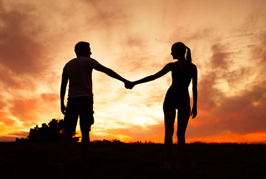 Couple holding hands in the sunset. 