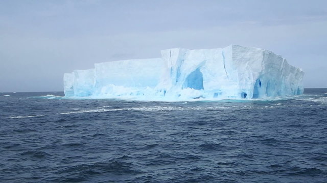 Tabular iceberg floating in rough seas of Drake Passage near Antarctica.
