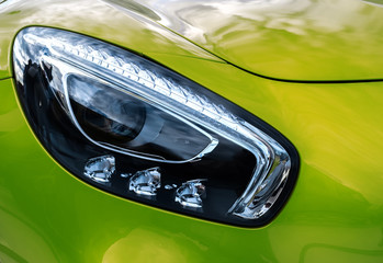Closeup headlights of modern sport green car. Car exterior detail.