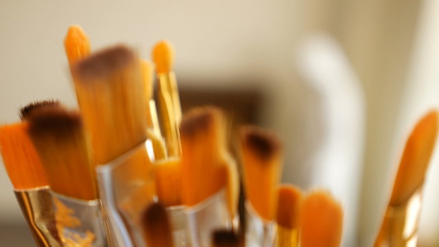 Artist paintbrushes. Set of different artist paint brushes in old crock close-up. Art studio concept. Selective focus footage with shallow DOF. 4K UHD video footage.