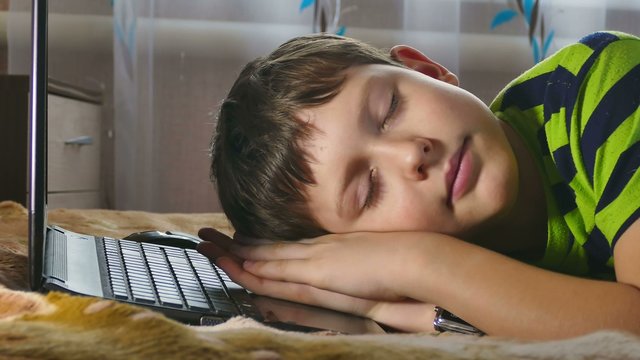 boy sleeping near the laptop tired