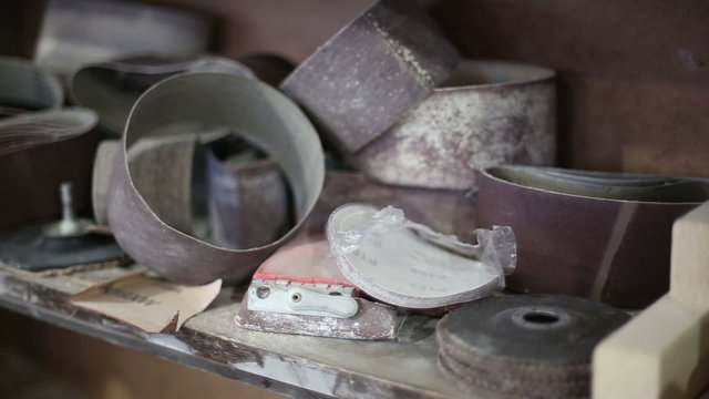 The stack of emery papers and other tools lying on a shelf in a carpentry workshop

