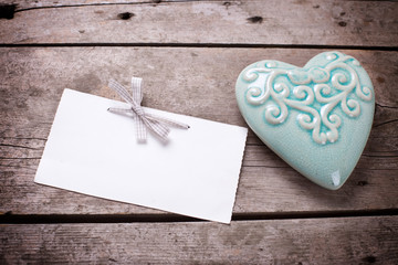 Turquoise decorative  heart and empty tag on aged wooden backgro