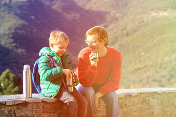father and son travel in mountains drinking hot tea