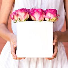 Bouquet of pink roses in a box  in the hands of the girl.
