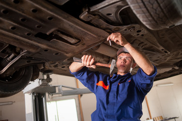 Fototapeta na wymiar Portrait of car mechanic working with tools under car in automob