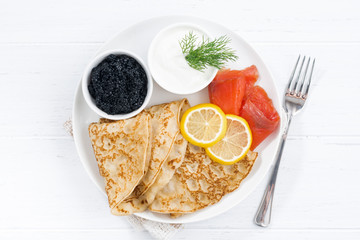 Traditional crepes with fish, sour cream and caviar, top view