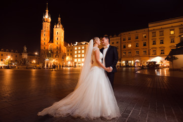 Marry the night. Beautiful young just married couple posing on the city square at night