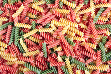 dried Italian colored pasta in the shape of a spiral closeup background
