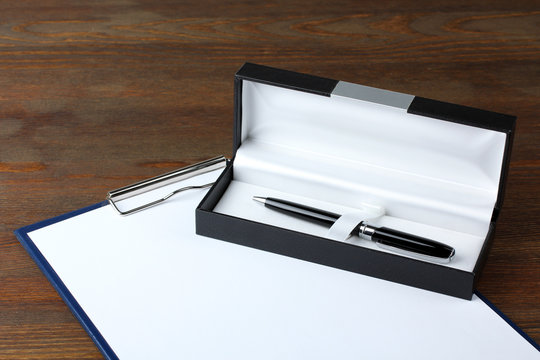Pen lying on a sheet of a contract or on a blank sheet to fill out on the wooden table