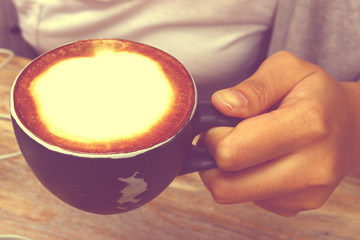 Hand holding a cup of coffee with close up shot in vintage tone, like instagram filter effect