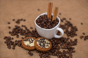 coffee beans cinnamon cookie white cup and saucer on a table brown texture close a lot of grain