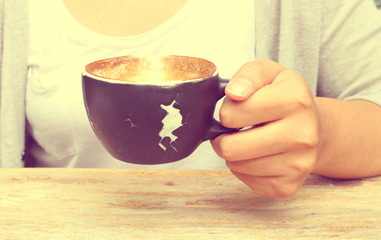 Hand holding a cup of coffee in vintage tone, like instagram filter effect