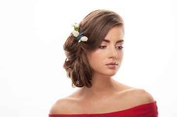 Young adorable brunette woman in red shirt with bare shoulders showing low bun hairstyle with flower headpiece on white background