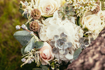 wedding bouquet with roses and succulents on green grass and woo