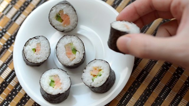 
Man takes sushi roll by hands. View from above.