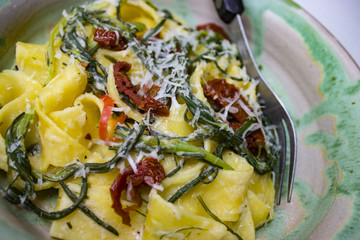 Barba di Frate und Papardelle mit Parmesanspänen und Tomaten in einem Teller mit Gabel