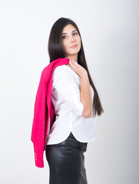 A young pretty slim asian woman standing in a leather skirt and white blouse. holding a red jacket on shoulderl
