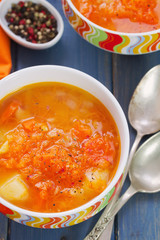 pumpkin soup in bowl with spoon on blue wooden background